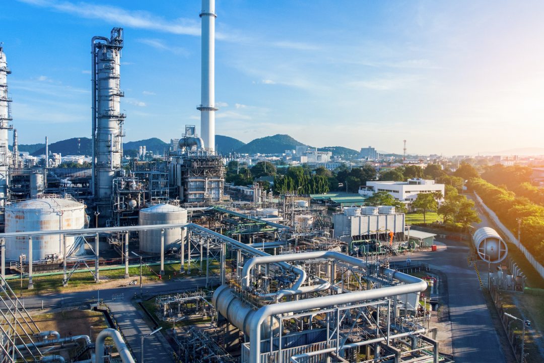 Aerial view of chemical oil refinery plant, power plant on blue sky background.